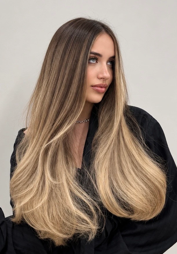 Cabello largo con raíz castaña y reflejos dorados hacia las puntas.